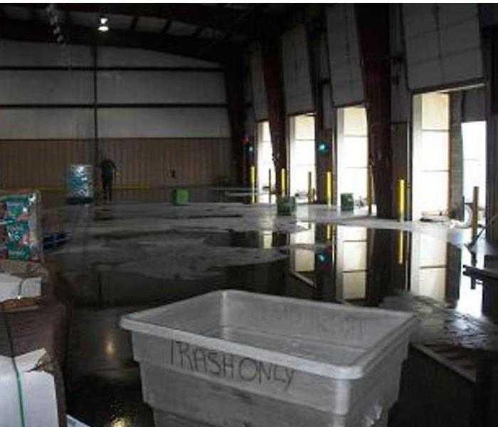 large puddles of water on a concrete floor in a warehouse, bay doors closeby