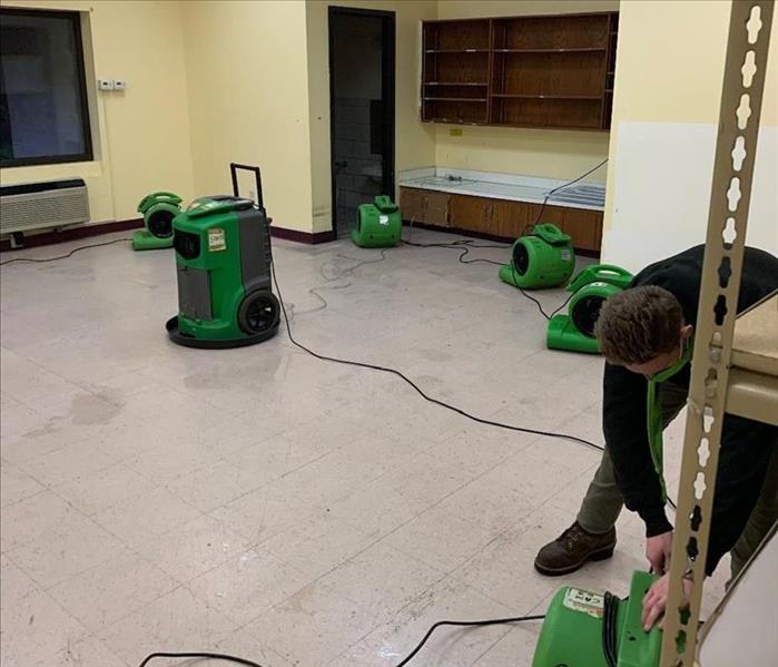 Drying with air movers positioned along walls and a dehumidifier in the middle of the room