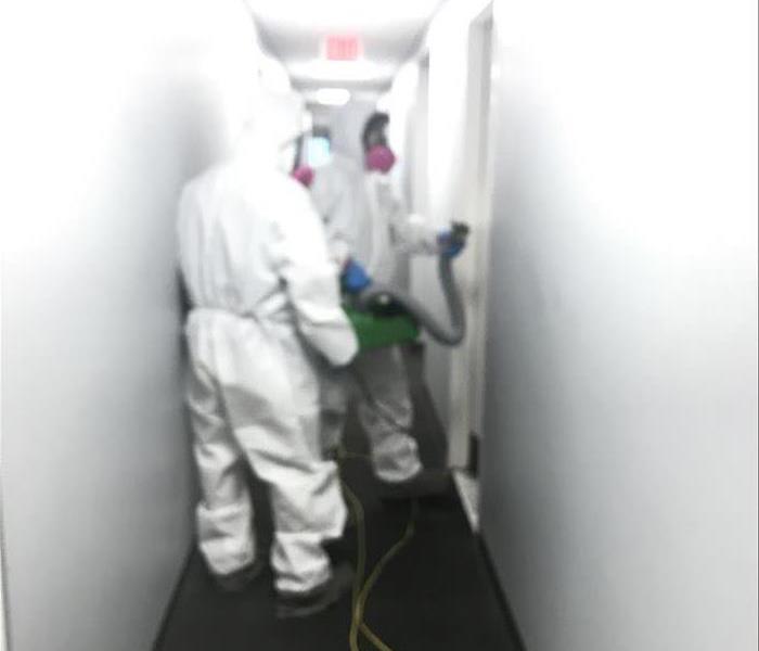 Two technicians spraying hallway with ULV