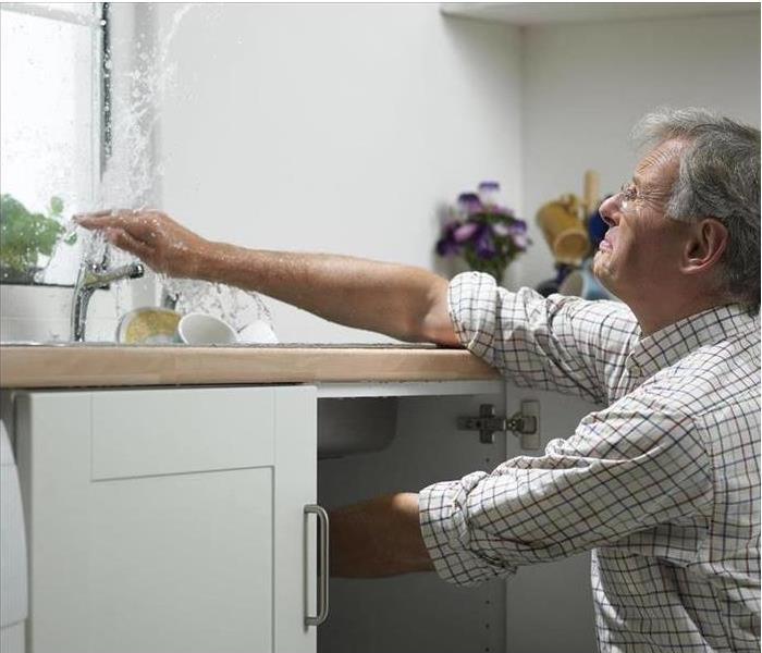 Man fixing leaking faucet in kitchen sink